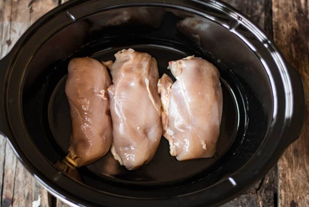 3 raw chicken breasts in a slow cooker.
