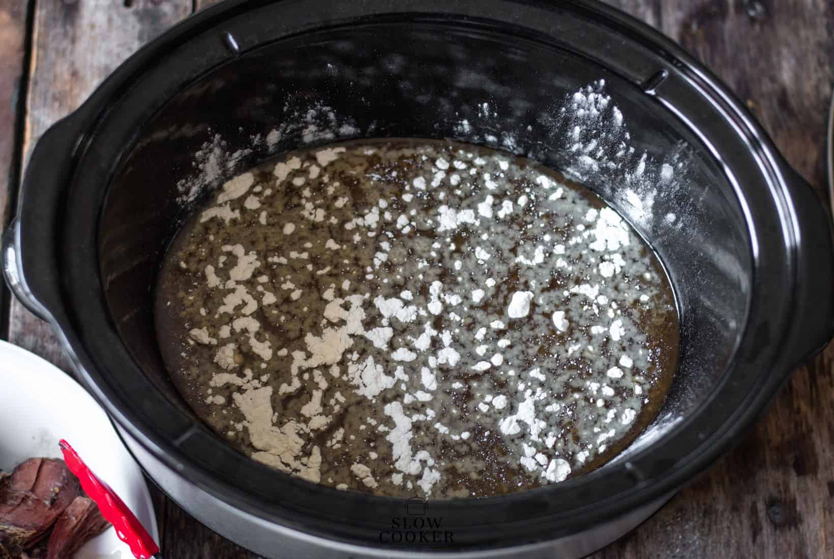 flour sprinkled over the sauce in the bottom of a slow cooker.