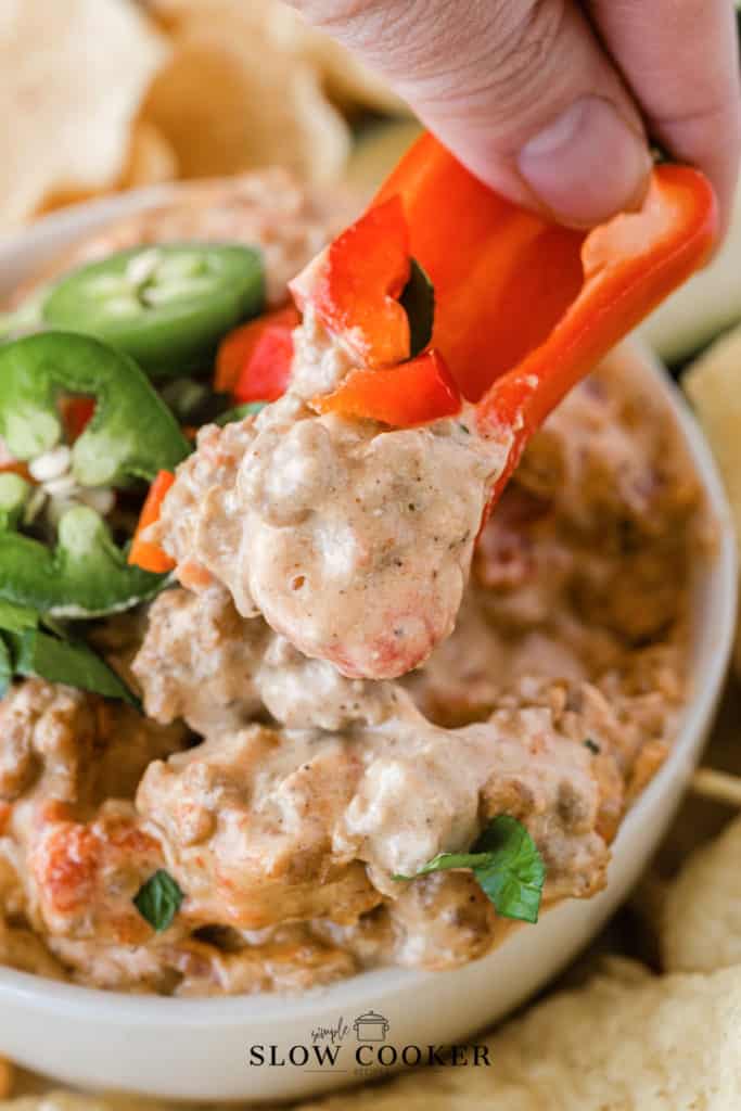 rotel dip being scooped up with a red bell pepper.