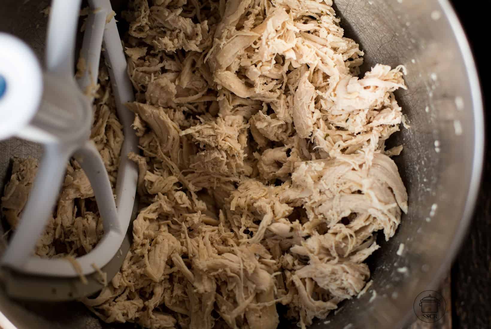 shredded chicken breast in a mixing bowl with a paddle.