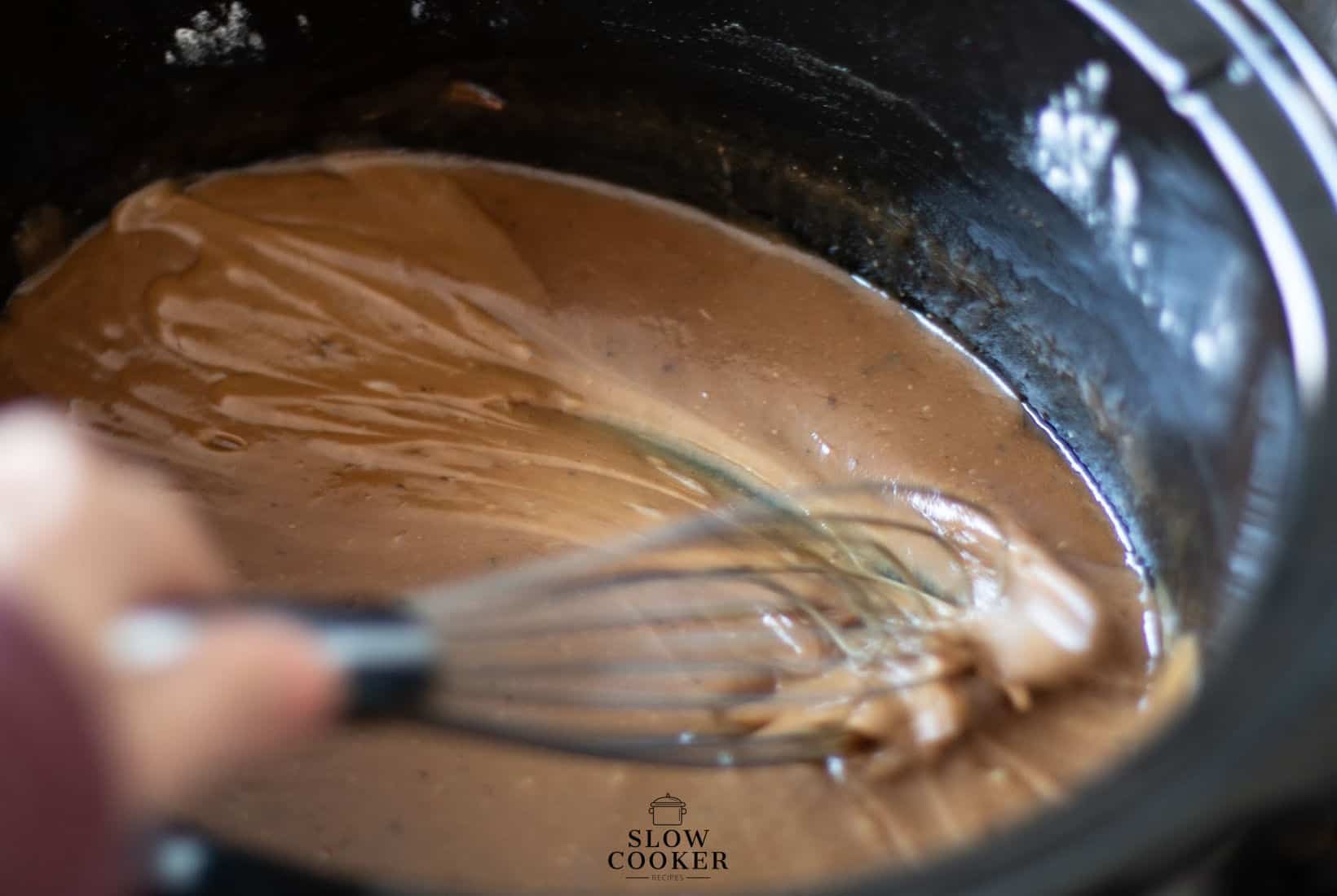 whisk stirring gravy in a slow cooker.