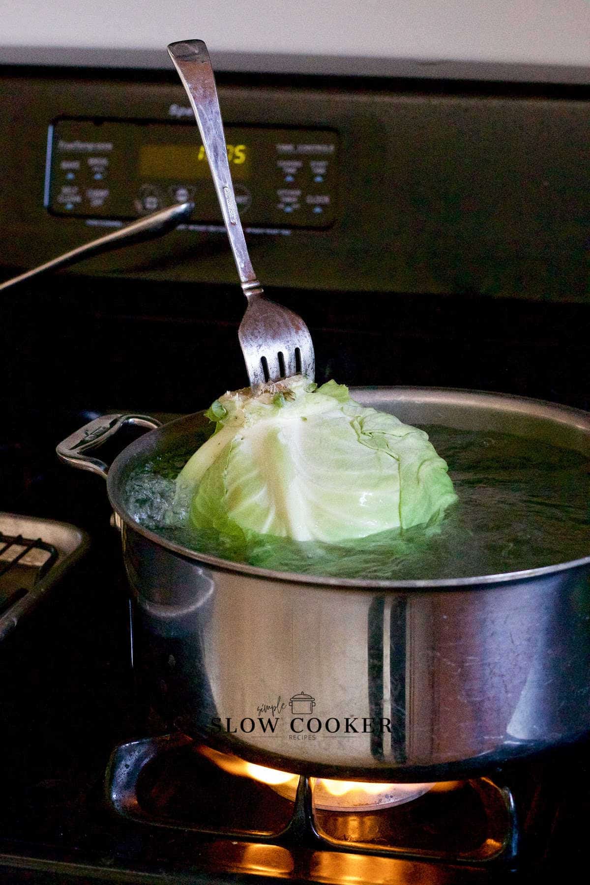 green cabbage being dunked in simmering water.