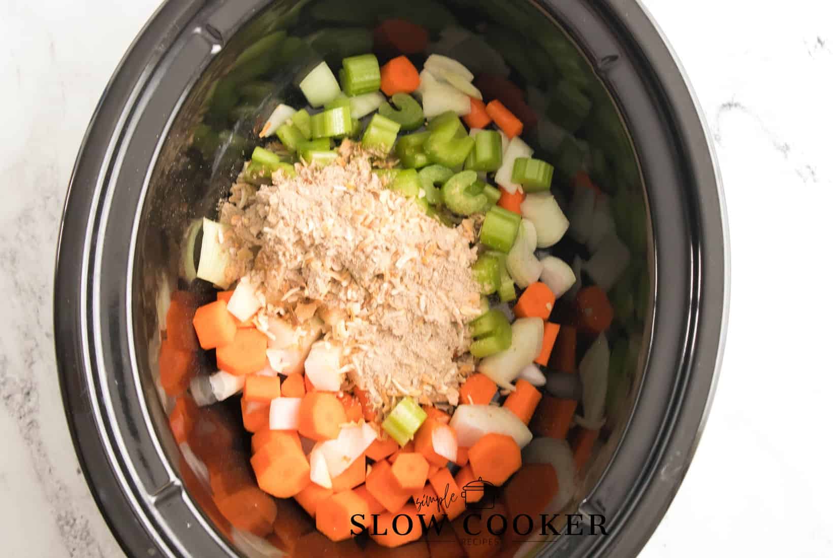 onion soup mix poured over cellery, carrots and onions in a slow cooker.