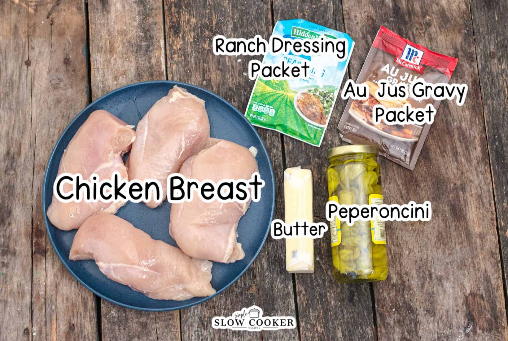 Slow Cooker Mississippi Chicken ingredients, chicken breast, ranch dressing packet, au jus gravy packet, butter, peperoncini, labeled.