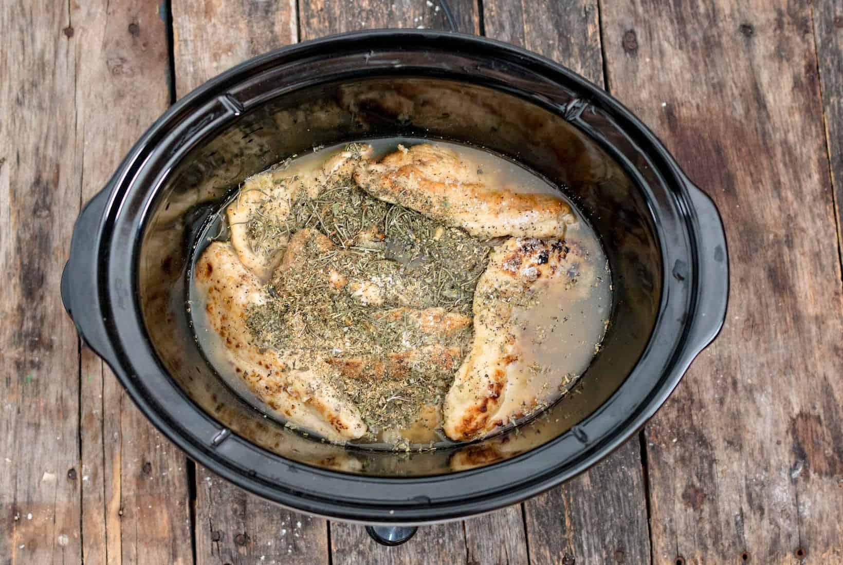 chicken stock added to the slow cooker along with the chicken and herbs for Marry Me Chicken.
