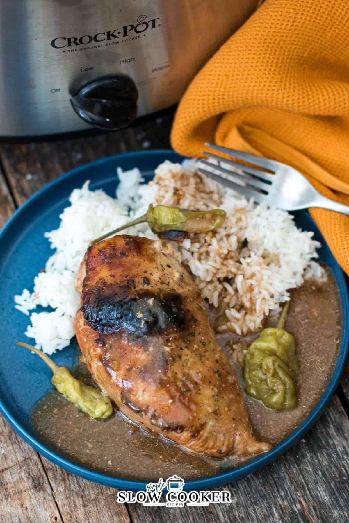 slow cooker mississippi chicken on a plate with sauce and white rice.